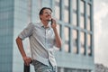 Man on the street. Happy young businessman talking on cell phone near business center Royalty Free Stock Photo