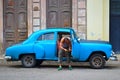 A man on the street repairs an old american car in Havana, Cuba