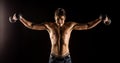 Man stretching arms outward doing a Standing Dumbbell Chest Fly. Studio composite over black. Royalty Free Stock Photo