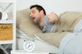 man stretching in bed alarmclock in foreground Royalty Free Stock Photo