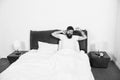 Man stretching in bed. Carefree guy enjoying morning. Wake up. Enjoying carefree morning. Lazy man happy waking up in