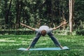 Man stretching hands and legs on green grass in park. Royalty Free Stock Photo