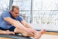 Man stretching hands to feet toes indoors