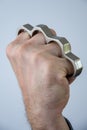 Man strikes brass knuckles on a light background, a prohibited weapon in a fight, heavy damage