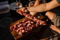 Man string meat pieces on the skewer and place them to the cutting board