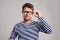 Man in striped t-shirt and eyeglasses against gray background. Royalty Free Stock Photo