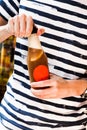 A man in a striped t-shirt opens kvass hands of a man holding a bottle with a drink close-up cold soda