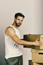 Man with strong arms standing among cardboard boxes