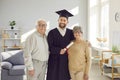 Man student in graduate gown and diploma in hands standing with senior old parents at home