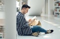 Man, student and reading in library with book for knowledge, education or learning at the university. Male learner in Royalty Free Stock Photo