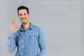 Man in studio in denim shirt doing okay sign with hand copy-space