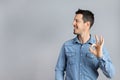 Man in studio in denim shirt doing okay sign with hand copy-space