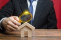 A man is studying a house through a magnifying glass. Fair value of real estate. Property valuation. Legal deal. Legality and