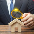 A man is studying a house through a magnifying glass. Fair value of real estate. Property valuation. Legal deal. Standards and Royalty Free Stock Photo