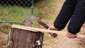 A man on a stump briskly chops a stick with an ax close-up.