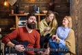 Man with stylish beard enjoying creative process. Musician entertaining his wife and daughter. Girls with smiling face