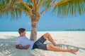 Man in stylish clothes relaxing under palm tree at tropical sandy beach at island luxury resort Royalty Free Stock Photo