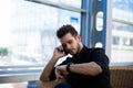 Male skilled broker watching on a wristwatch and calling via cellphone during work day in office Royalty Free Stock Photo