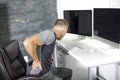 Man suffering from backache while sitting at computer desk in office Royalty Free Stock Photo
