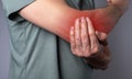 Man suffering from elbow pain and holding painful hand with red point closeup. Hand injury. Health care, joint diseases