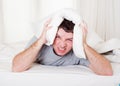 Man suffering hangover and headache with pillow on