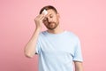 Man suffering from heat stuffiness wiping sweat on forehead with paper napkin isolated on pink wall Royalty Free Stock Photo