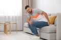 Man suffering from hemorrhoid on sofa