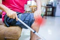 Man suffering from knee pain and walking stick sitting on sofa Royalty Free Stock Photo