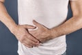 Man suffering from pain in his side. Blue background. Stomach, liver pain, pancreas, kidneys