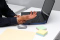 Man suffering from pain in his wrist due to Carpal Tunnel Syndrome while working in his office with his laptop and mouse