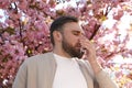 Man suffering from seasonal pollen allergy near blossoming tree outdoors Royalty Free Stock Photo