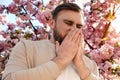 Man suffering from pollen allergy near blossoming tree outdoors Royalty Free Stock Photo
