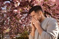 Man suffering from pollen allergy near blossoming tree outdoors Royalty Free Stock Photo