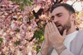 Man suffering from seasonal pollen allergy near tree outdoors Royalty Free Stock Photo