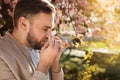 Man suffering from seasonal pollen allergy near blossoming tree outdoors Royalty Free Stock Photo