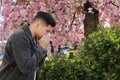 Man suffering from seasonal pollen allergy near blossoming tree outdoors Royalty Free Stock Photo