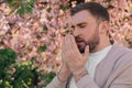 Man suffering from seasonal pollen allergy near blossoming tree outdoors Royalty Free Stock Photo
