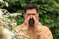 Man suffering from seasonal pollen allergy near tree on spring day Royalty Free Stock Photo