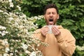 Man suffering from pollen allergy near blossoming tree on spring day Royalty Free Stock Photo