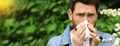 Man suffering from seasonal pollen allergy near blossoming tree on spring day. Banner design with space for text Royalty Free Stock Photo