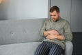 Man suffering stomach ache sitting on a couch in the living room at home. Royalty Free Stock Photo