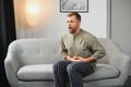 Man suffering stomach ache sitting on a couch in the living room at home. Royalty Free Stock Photo