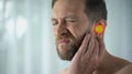 Man suffers from earache, otitis, hearing problems, spot indicates pain, closeup