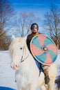 Man in suit of ancient viking riding big white horse