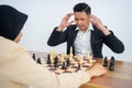 Man in suit confused looking chess pieces while playing chess
