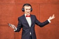 Man in a suit is dancing. young guy is listening to music in big headphones through smartphone. concept of good mood and Royalty Free Stock Photo