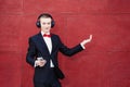 Man in a suit is dancing. Young guy is listening to music in big headphones through smartphone. Concept of good mood and Royalty Free Stock Photo