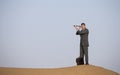 Man in a suit in a desert with a spyglass Royalty Free Stock Photo