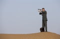 Man in a suit in a desert with a spyglass Royalty Free Stock Photo