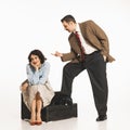 Man in suit gesturing at seated woman on the floor, suggesting confrontation, dispute. Young elegant woman expressing Royalty Free Stock Photo